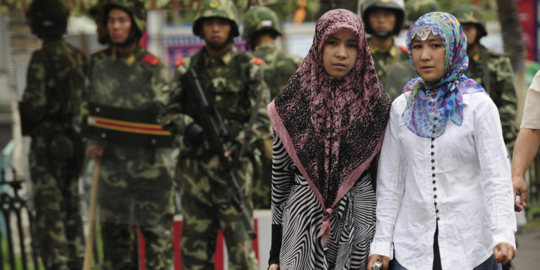 Two ethnic Uighur women pass Chinese par